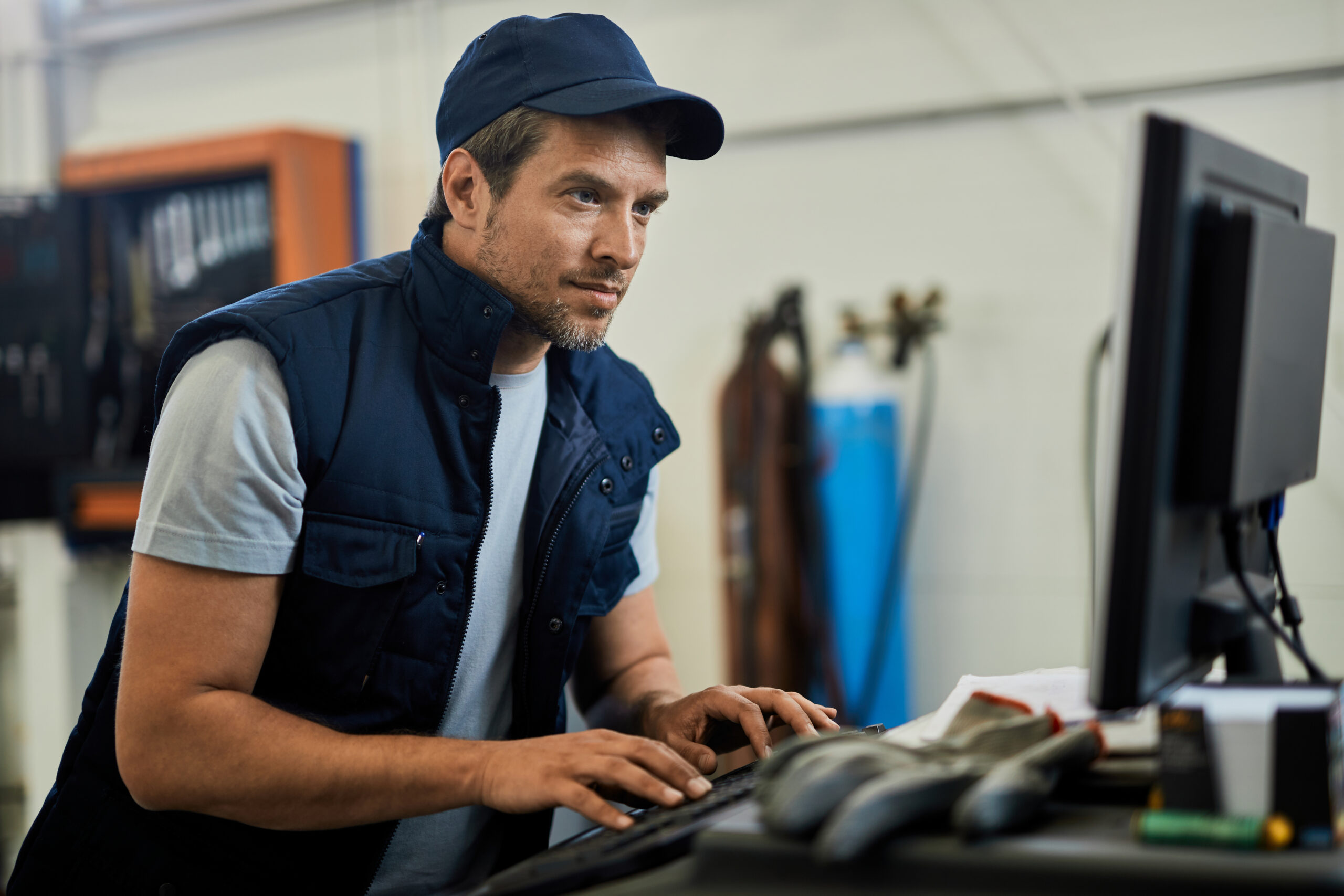 Auto repairman working on a computer in a workshop.